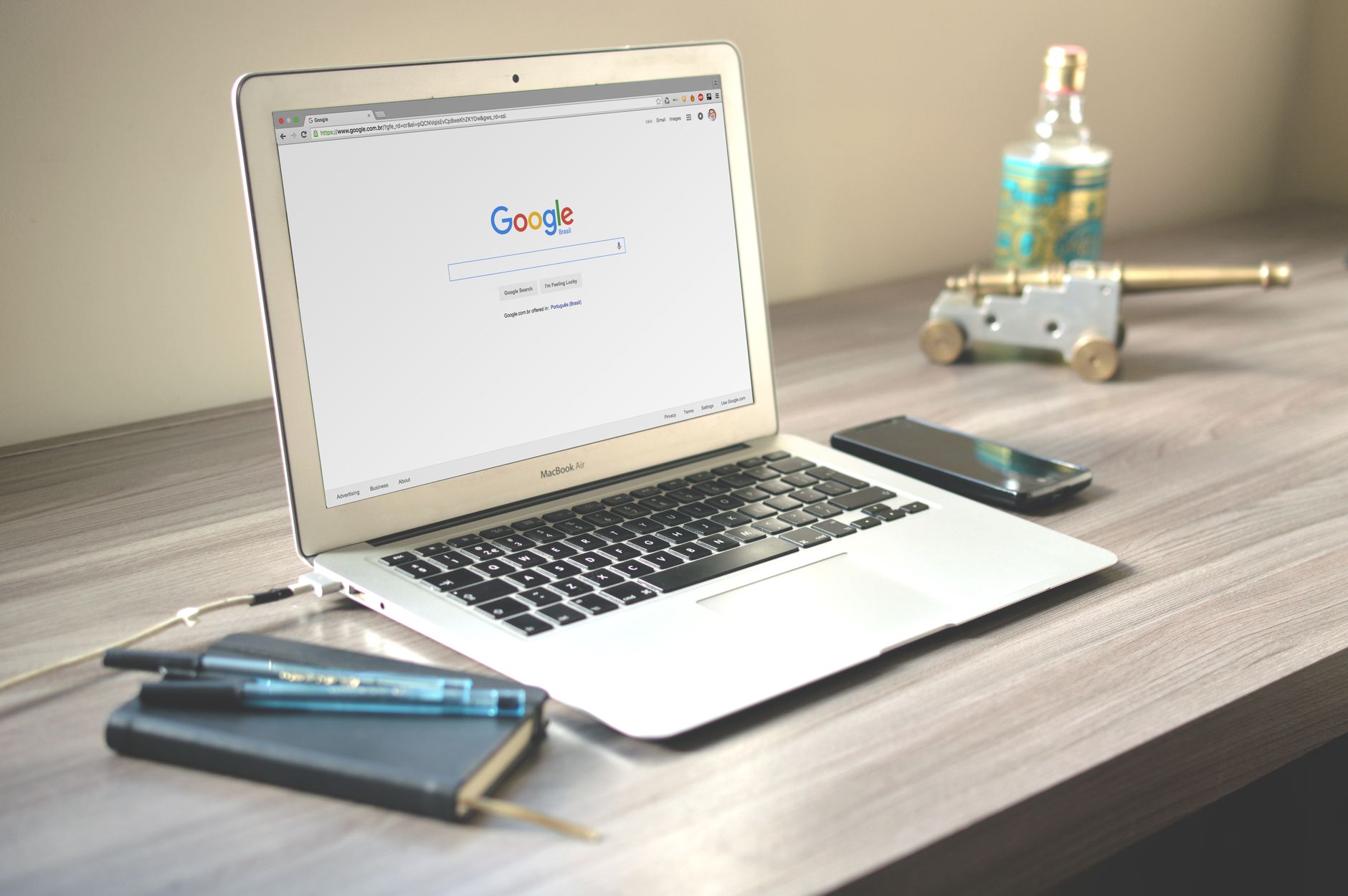 Notebook exibe pesquisa do Google ao lado de celular e caderno