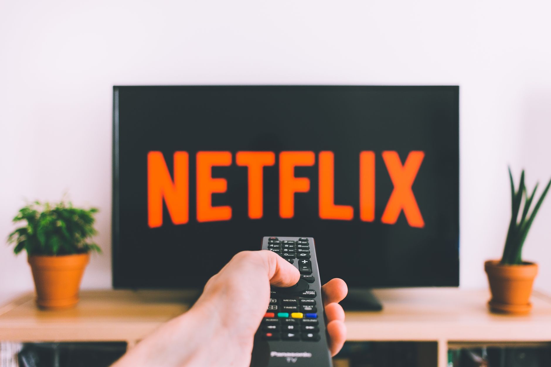 Controle remoto diante da Netflix após reajuste dos planos Pessoa usa controle remoto diante da tela da Netflix planos